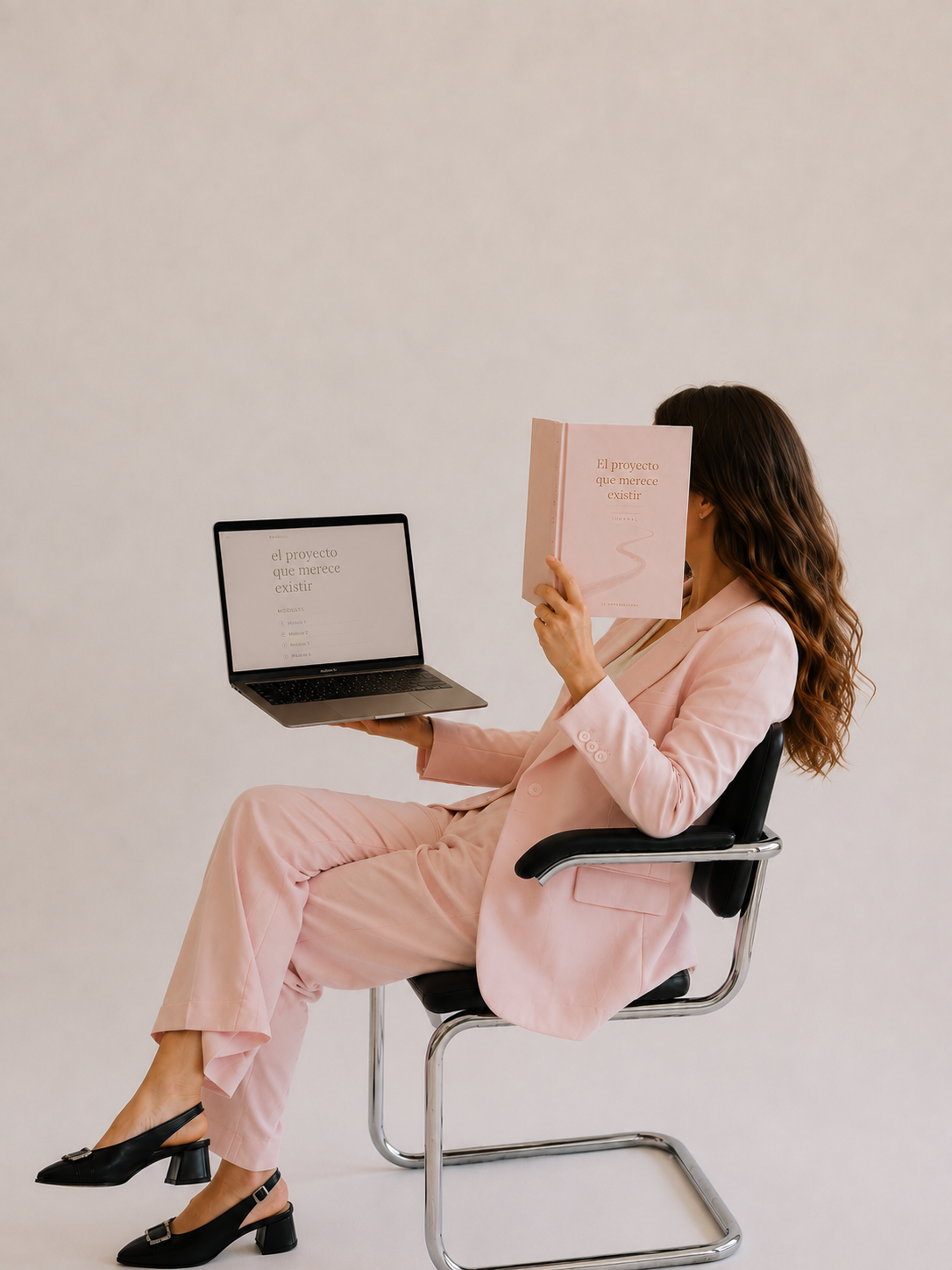 La fundadora sentada en una silla, con el journal en una mano y el portátil del curso en la otra